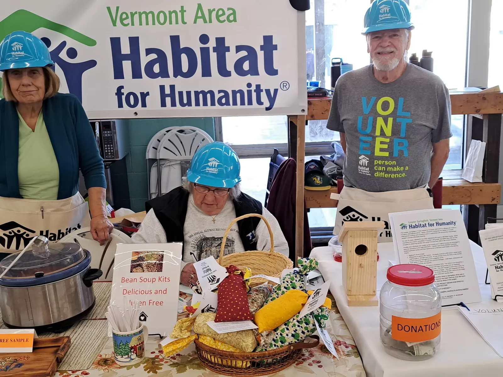 Volunteers at the Vermont Apple Festival table with a Habitat banner and donation jar