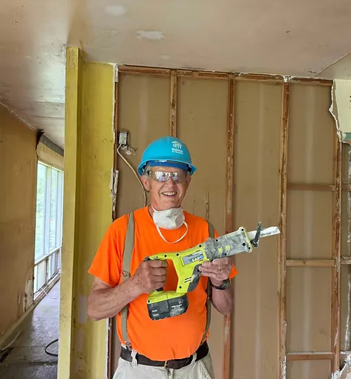 Volunteer in a hard hat using a reciprocating saw during an interior build
