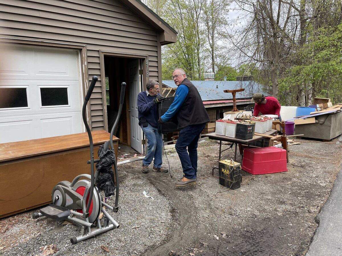 Volunteers clearing furniture and debris outside a garage during a site cleanup