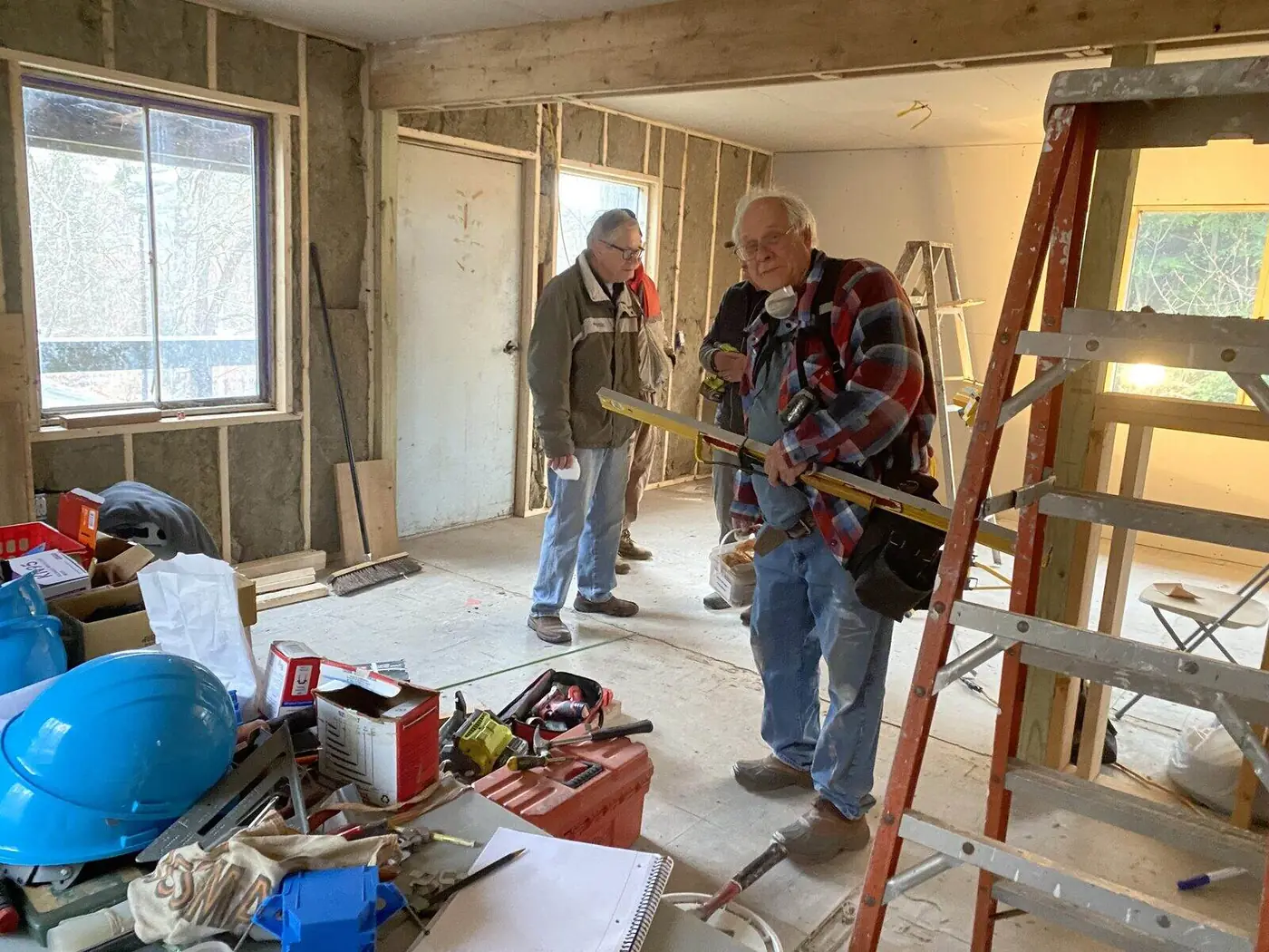 Volunteers checking a wall frame with a level inside a home under construction